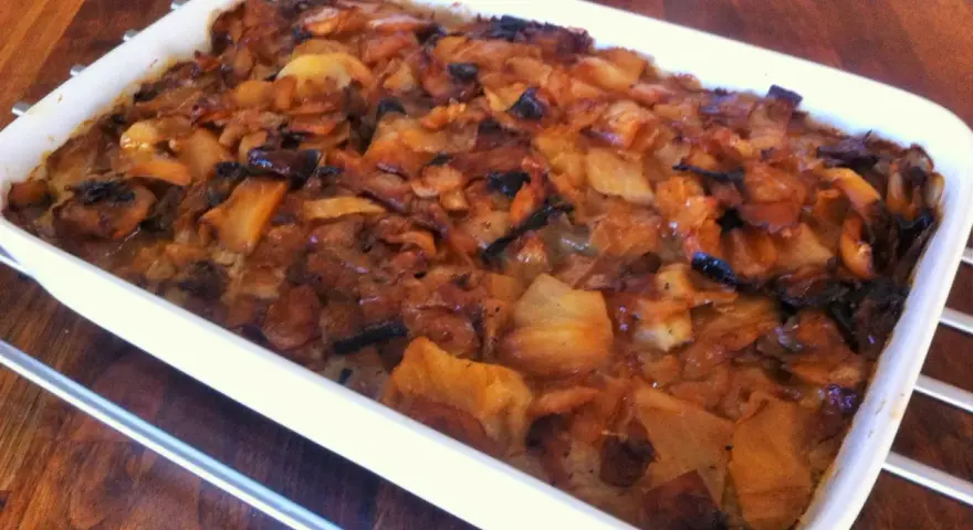 En nygräddad farmors kålpudding i en vit ugnsform, gyllene och inbjudande.