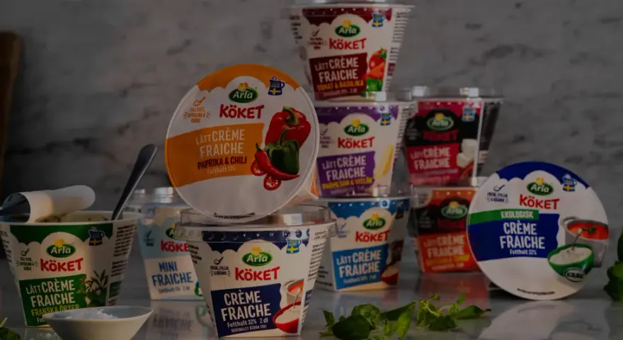 Various Arla Köket crème fraîche tubs, some open, with herbs and a bowl of salt.
