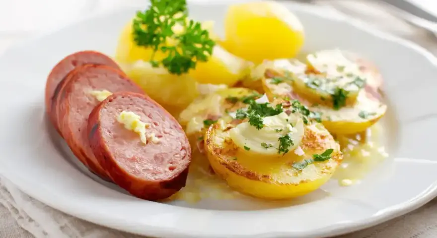 Skivad falukorv med smör och persilja, serverad med kokt potatis och en krämig sås. Bra att veta om man kan frysa falukorv.