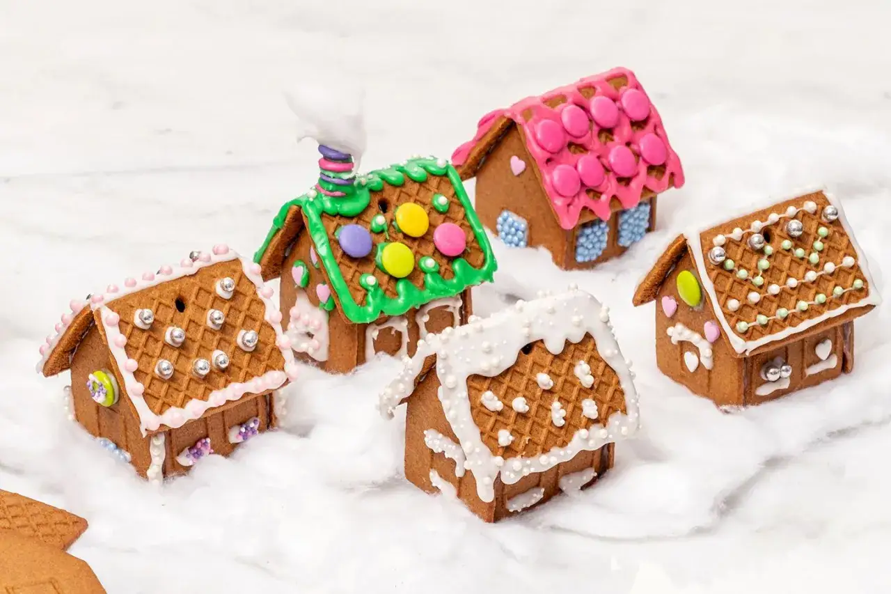 Små, dekorerade pepparkakshus med glasyr och godis, som om de vore små vinterhus. Perfekt för att limma pepparkakshus till jul.