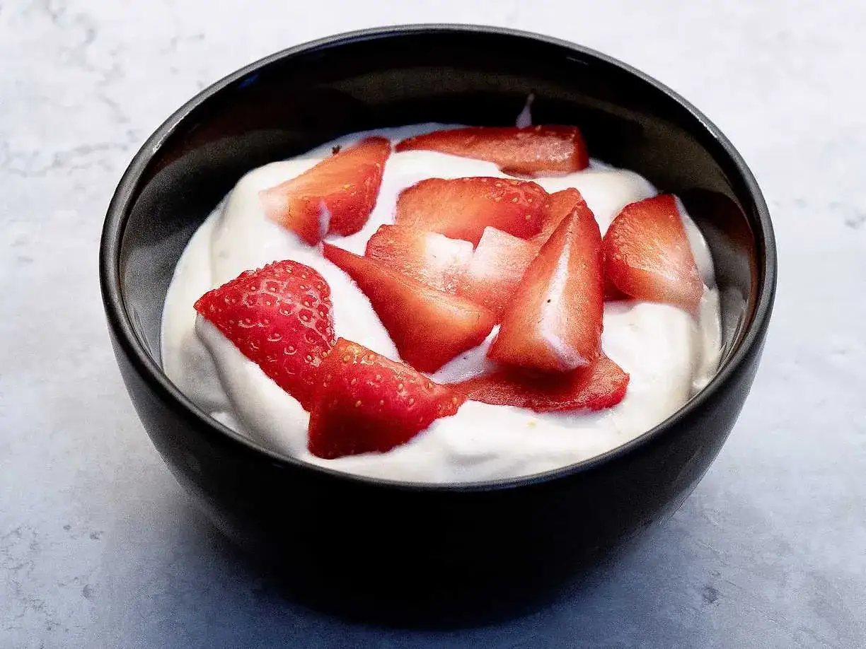 En skål med krämig hemmagjord glass toppad med färska jordgubbsbitar. En perfekt sommardessert.