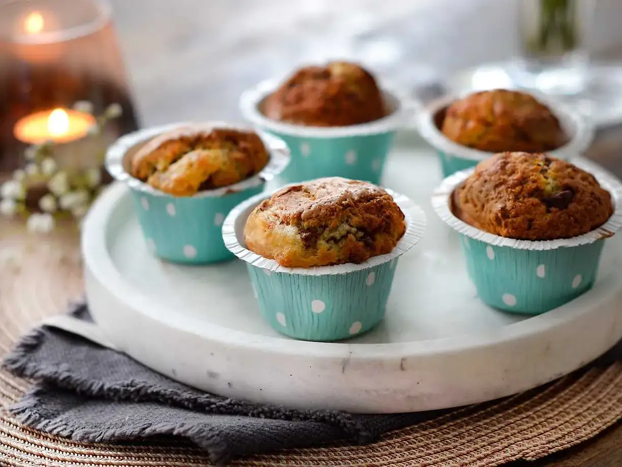 Nybakade muffins i ljusblåa pappersformar med prickar, perfekta att baka i airfryer. En mysig stund med tända ljus.