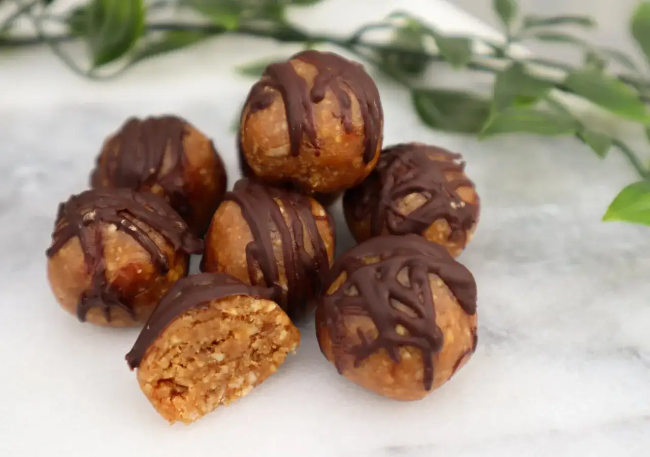 Små, runda bollar med chokladöverdrag, perfekta att baka med dadlar. En är uppskuren och visar en kornig insida.