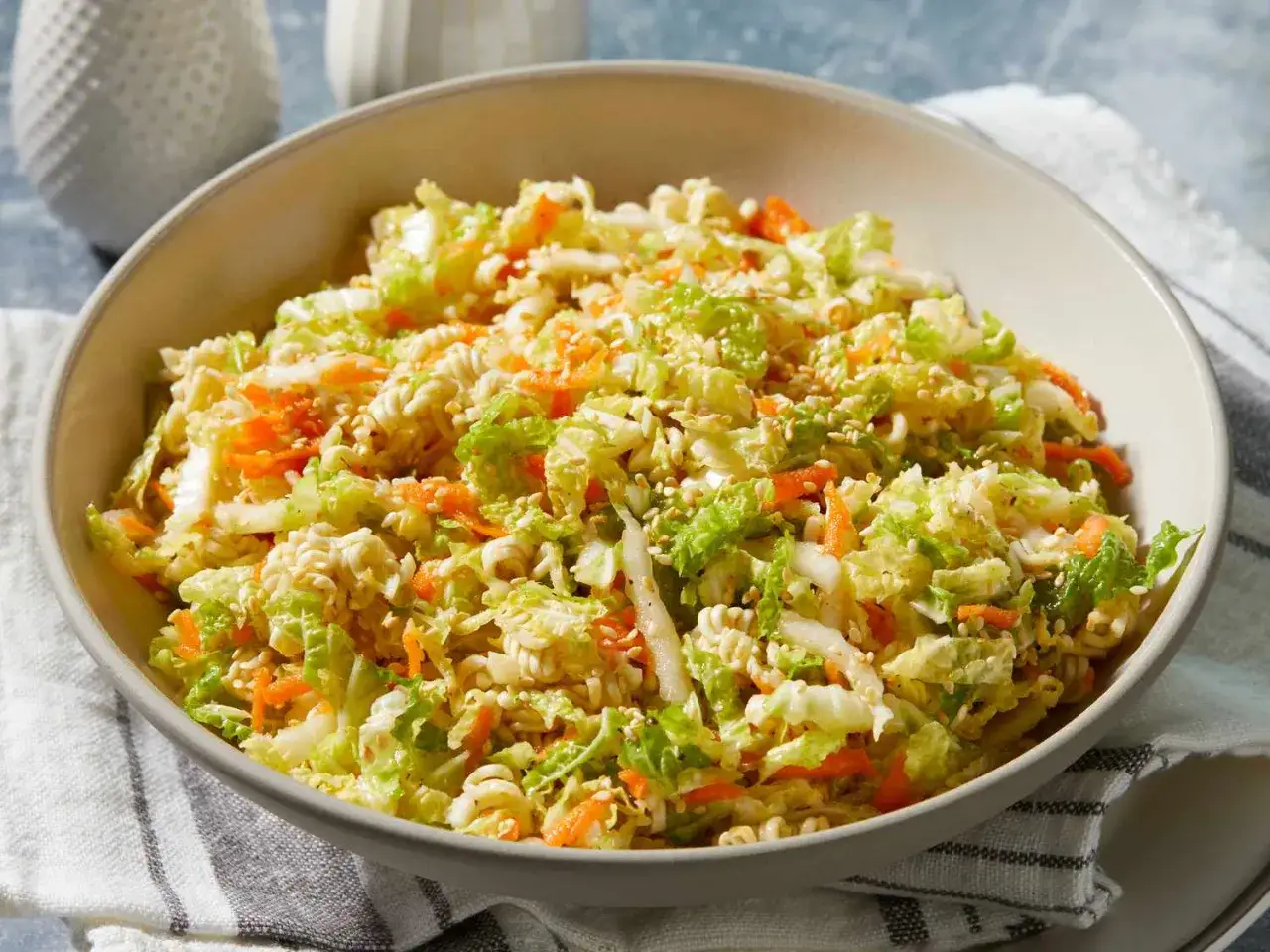 En skål med krispig asiatisk kålsallad med strimlad kål, morötter och sesamfrön.