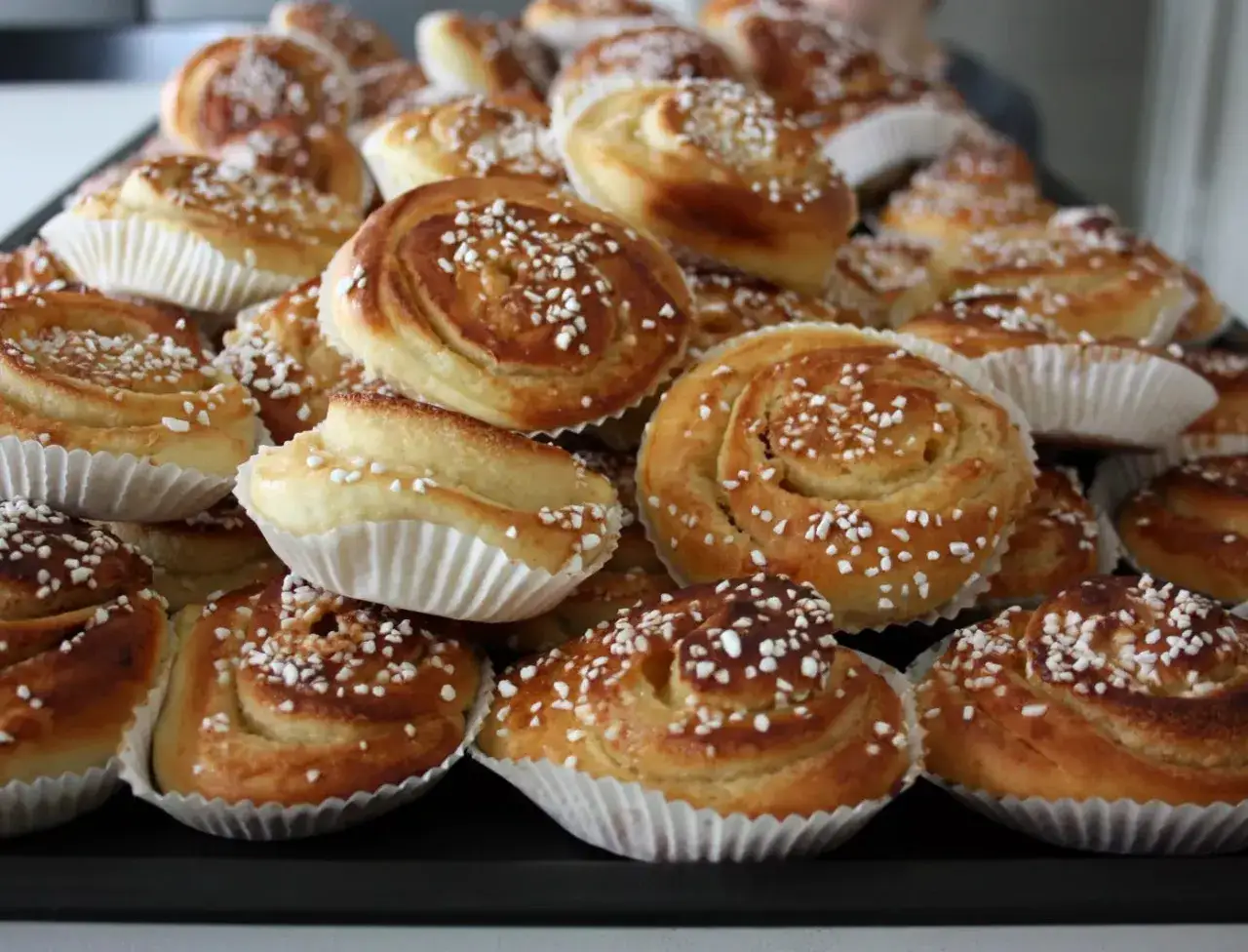 En stor hög med nybakade bullar med mandelmassa, toppade med pärlsocker. Perfekt för fikat!