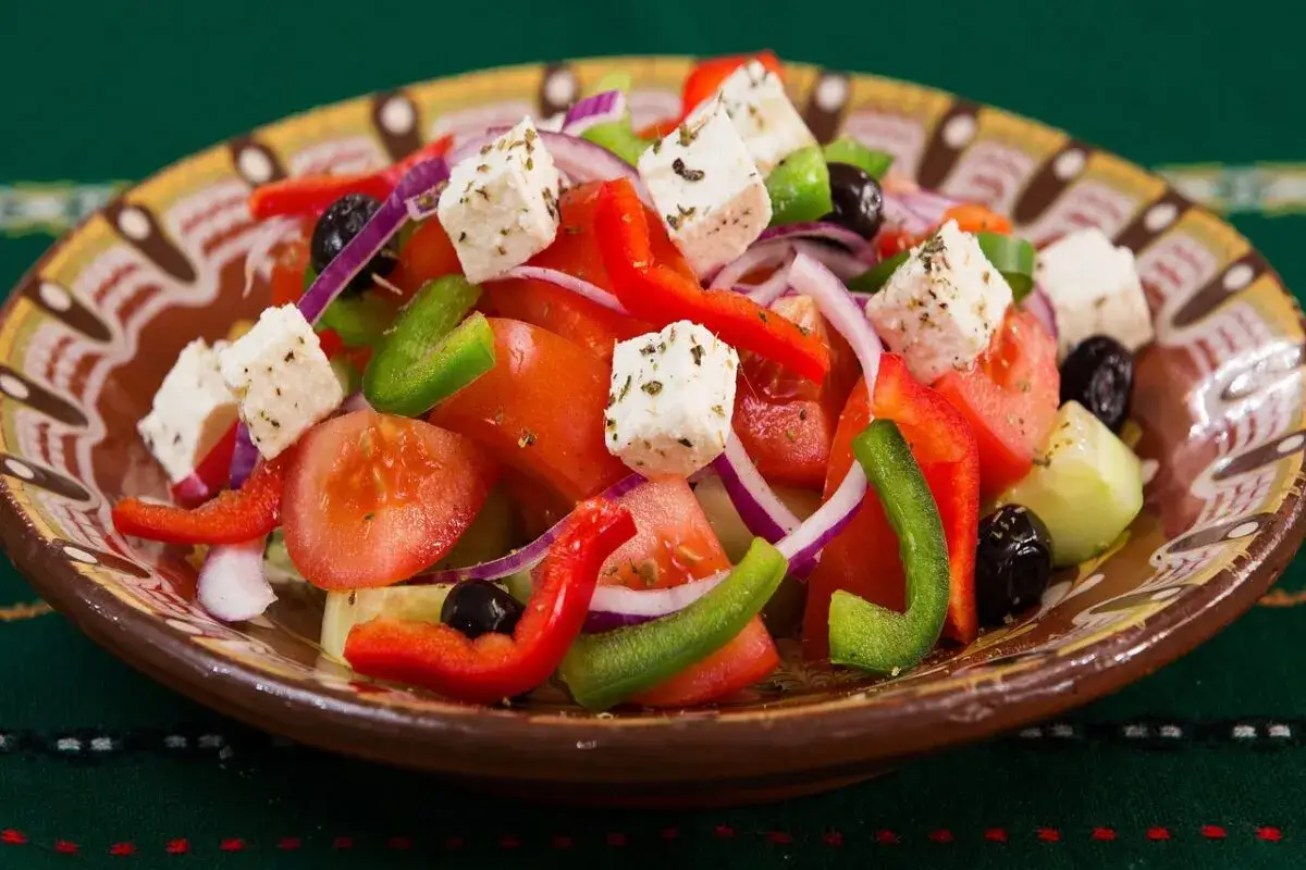 En fräsch grekisk sallad med tomater, gurka, paprika, rödlök, oliver och fetaost. En klassisk grekisk matupplevelse.