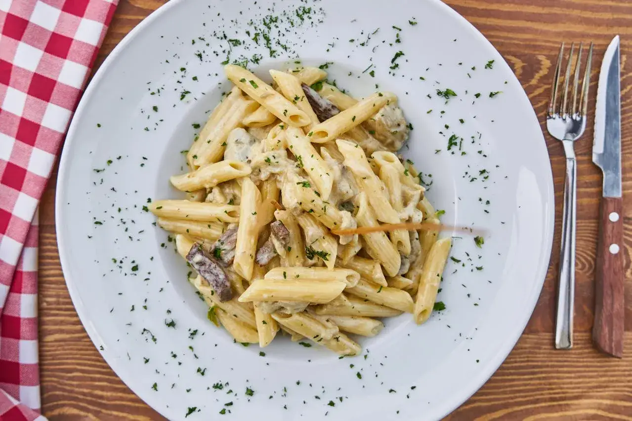 En krämig pastarätt med penne, svamp och köttstrimlor, strödd med persilja. En perfekt portion, undrar hur mycket pasta per person som är lagom?