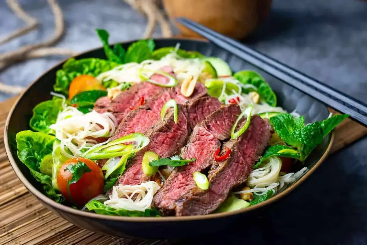 En läcker asiatisk biffsallad med saftigt, tunt skivat nötkött, risnudlar, färska grönsaker och mynta.