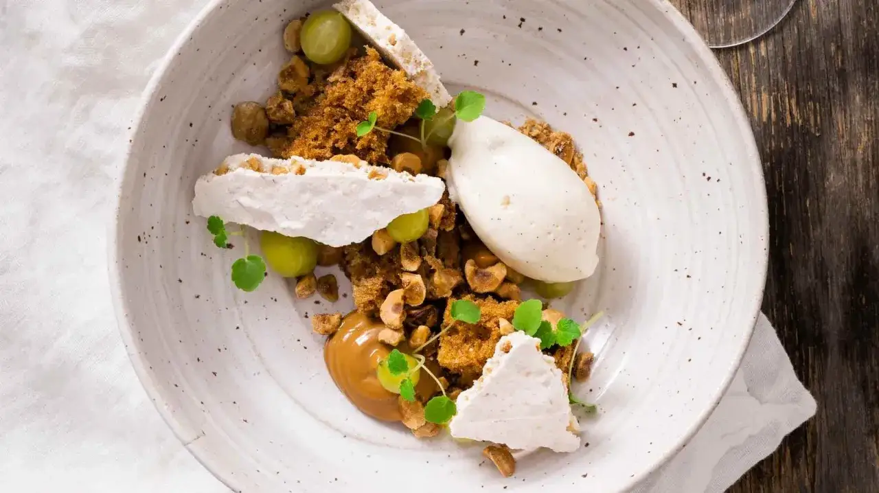 En elegant dessert med vaniljglass, maräng, nötter, druvor och en karamellsås. En sann muggkaka vanilj-upplevelse.