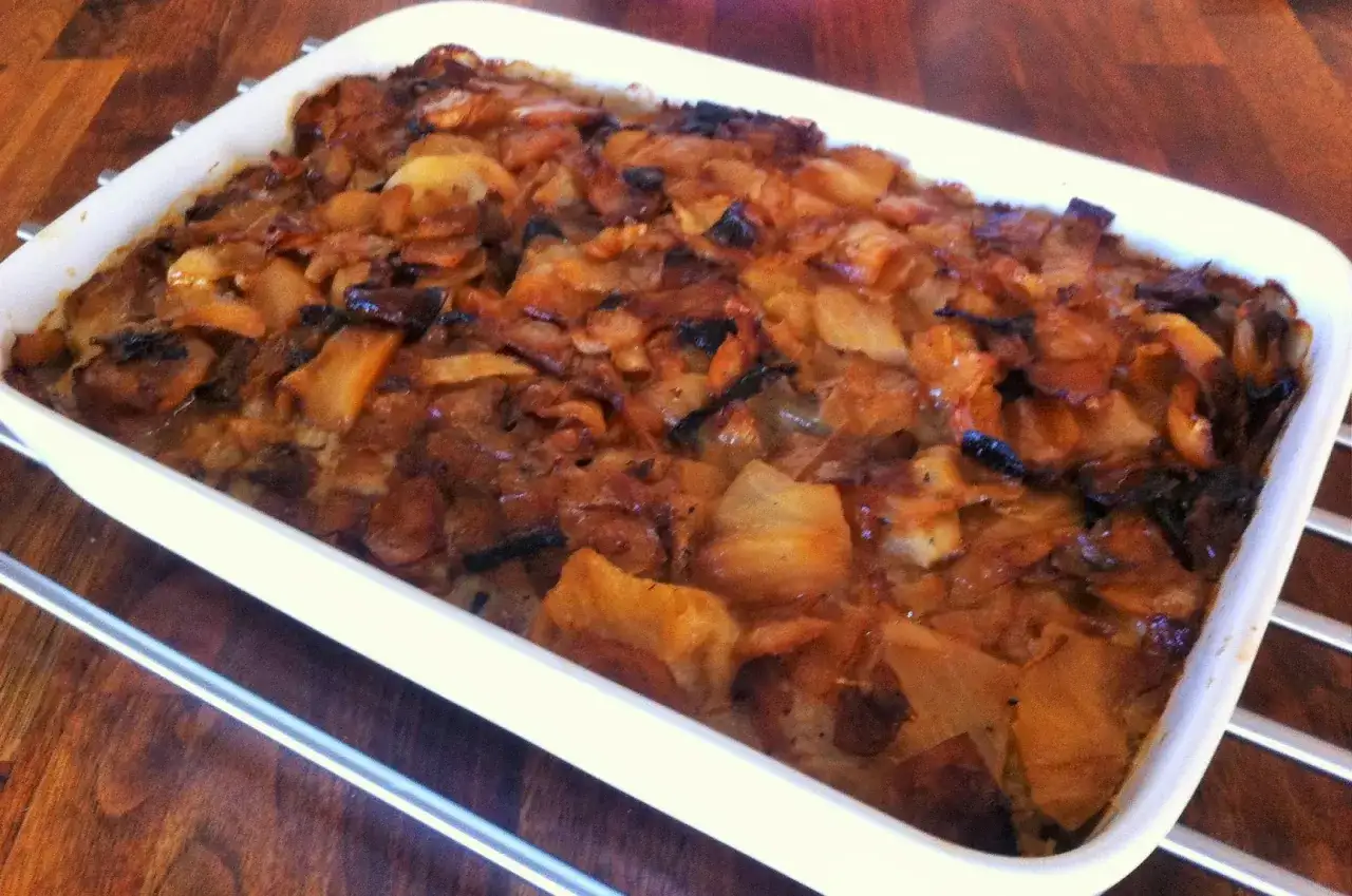 En nygräddad farmors kålpudding i en vit form, gyllene och inbjudande.