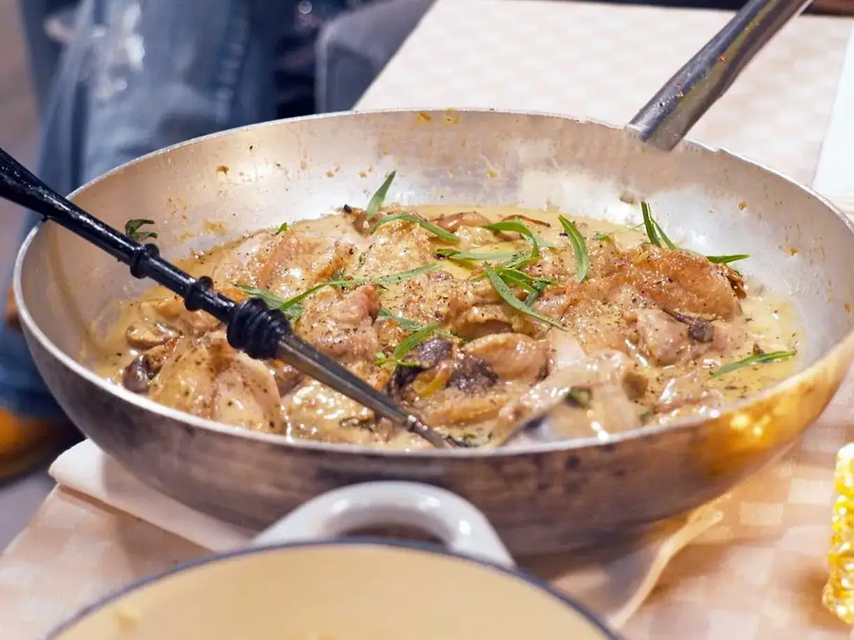 En panna med krämig coq au vin blanc, kycklingbitar, champinjoner och örter.