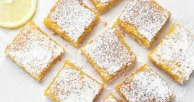 Citronkaka i långpanna, pudrad med florsocker, skuren i fyrkanter. En citronskiva syns i övre vänstra hörnet.