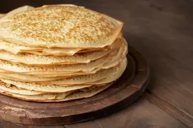 En hög med gyllene pannkakor på en träbricka. Perfekt för att frysa in och njuta av senare.