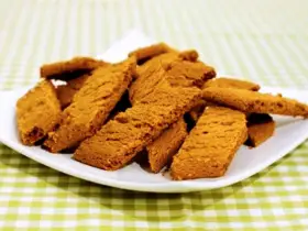En hög med gyllene, krispiga kola kakor på en vit tallrik, redo att avnjutas.