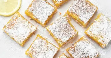 Citronkaka i långpanna, pudrad med florsocker, skuren i fyrkanter. En citronskiva syns i övre vänstra hörnet.