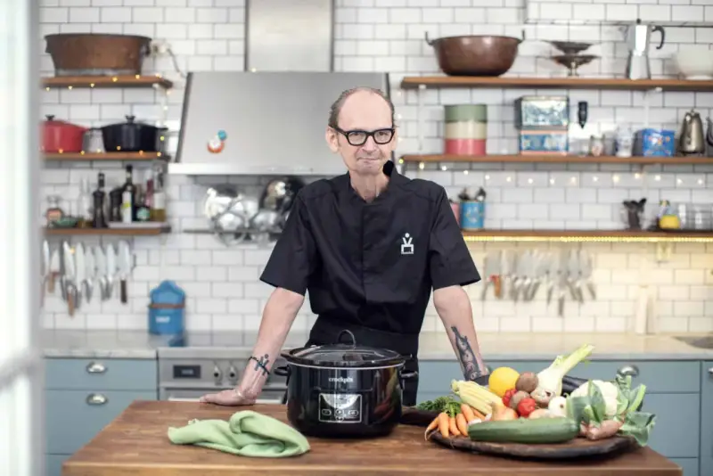 Erik Videgård i köket med en slow cooker och färska grönsaker.