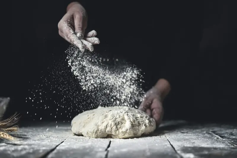 Händer strör mjöl över deg. En berättelse om svenskt bröd och kärleken till bakning med bra **bread flour svenska**.