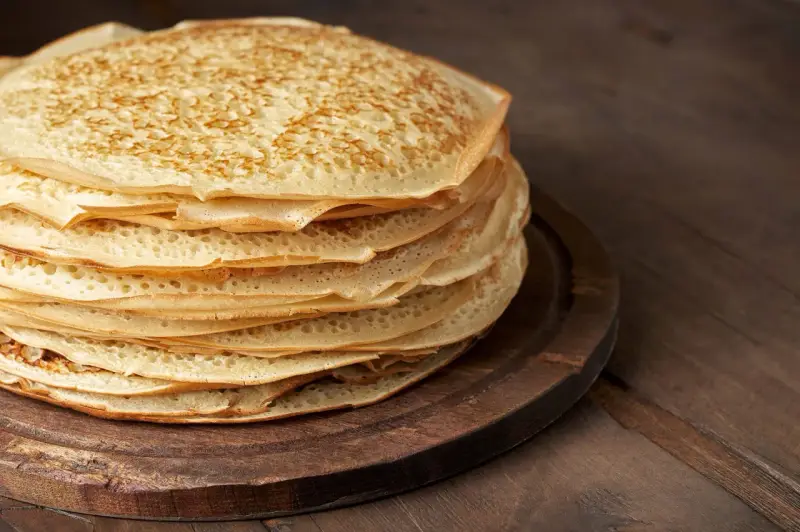 En hög med gyllene pannkakor på en träbricka. Perfekt för att frysa in och njuta av senare.