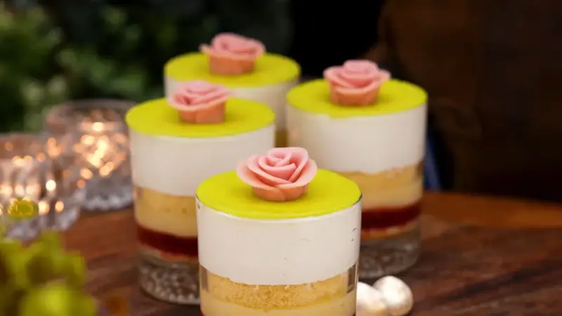 Fyra små prinsesstårta i glas, dekorerade med rosa marsipanrosor och gul marsipanlock. En festlig dessert.